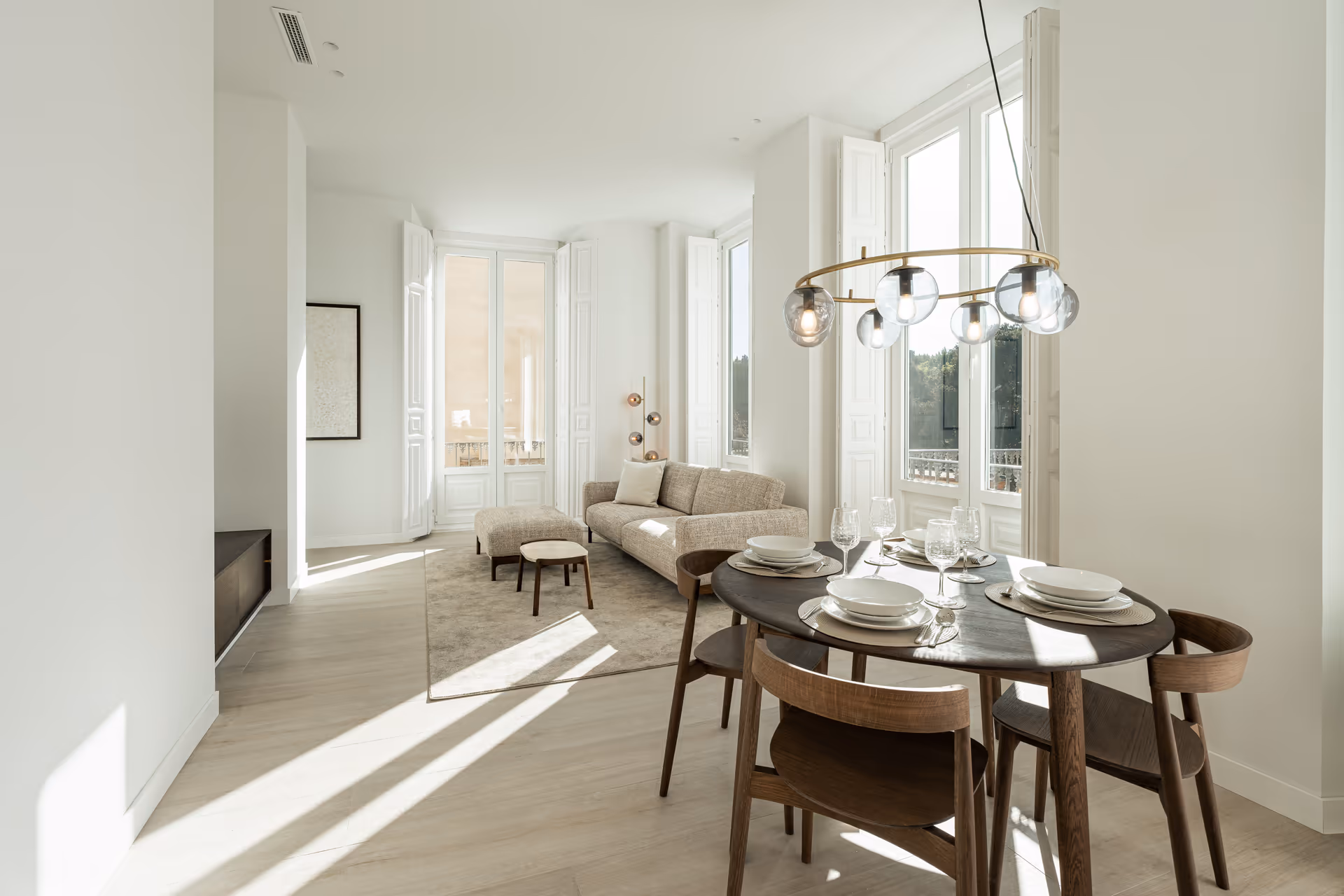 Sunlight streams into the open-plan living and dining area of the Aurum residence, highlighting the light wood floors and modern furniture