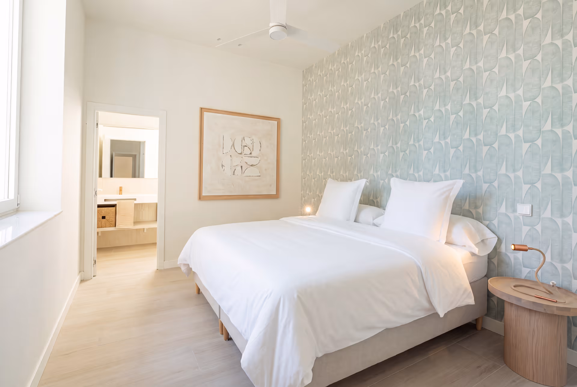 Bedroom in the Azuri residence with a double bed, textured white bedspread, and pale green patterned wallpaper behind the headboard