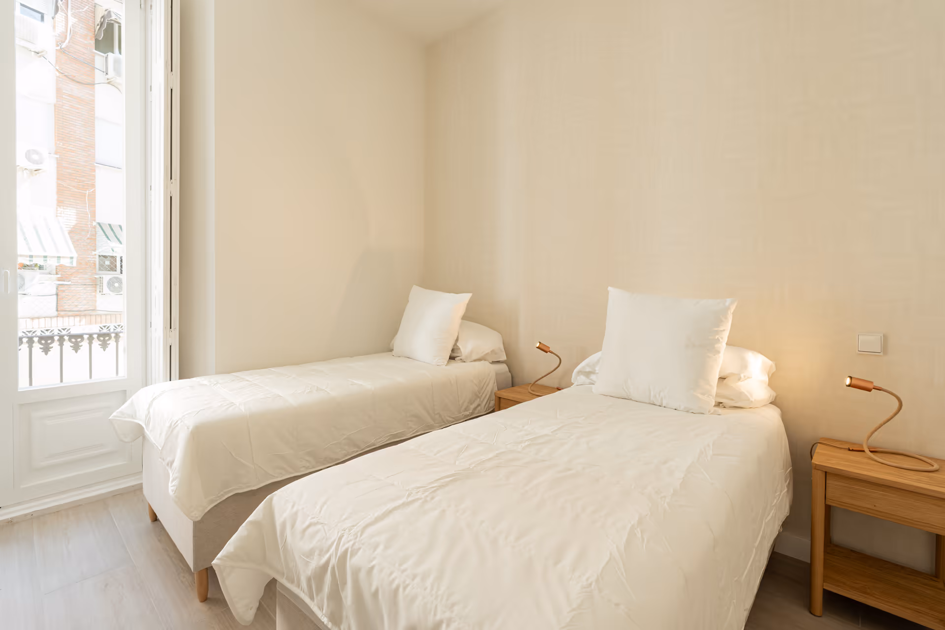 Twin bedroom in the Azuri residence with two single beds, white bedding, and a glass door opening onto a balcony