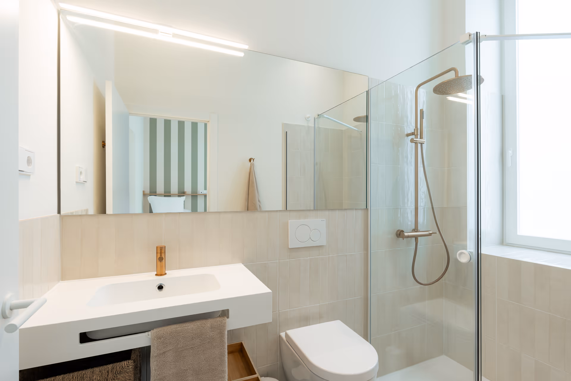 Bathroom in the Oliva residence with a white sink, bronze tap, and a walk-in rain shower with glass screen