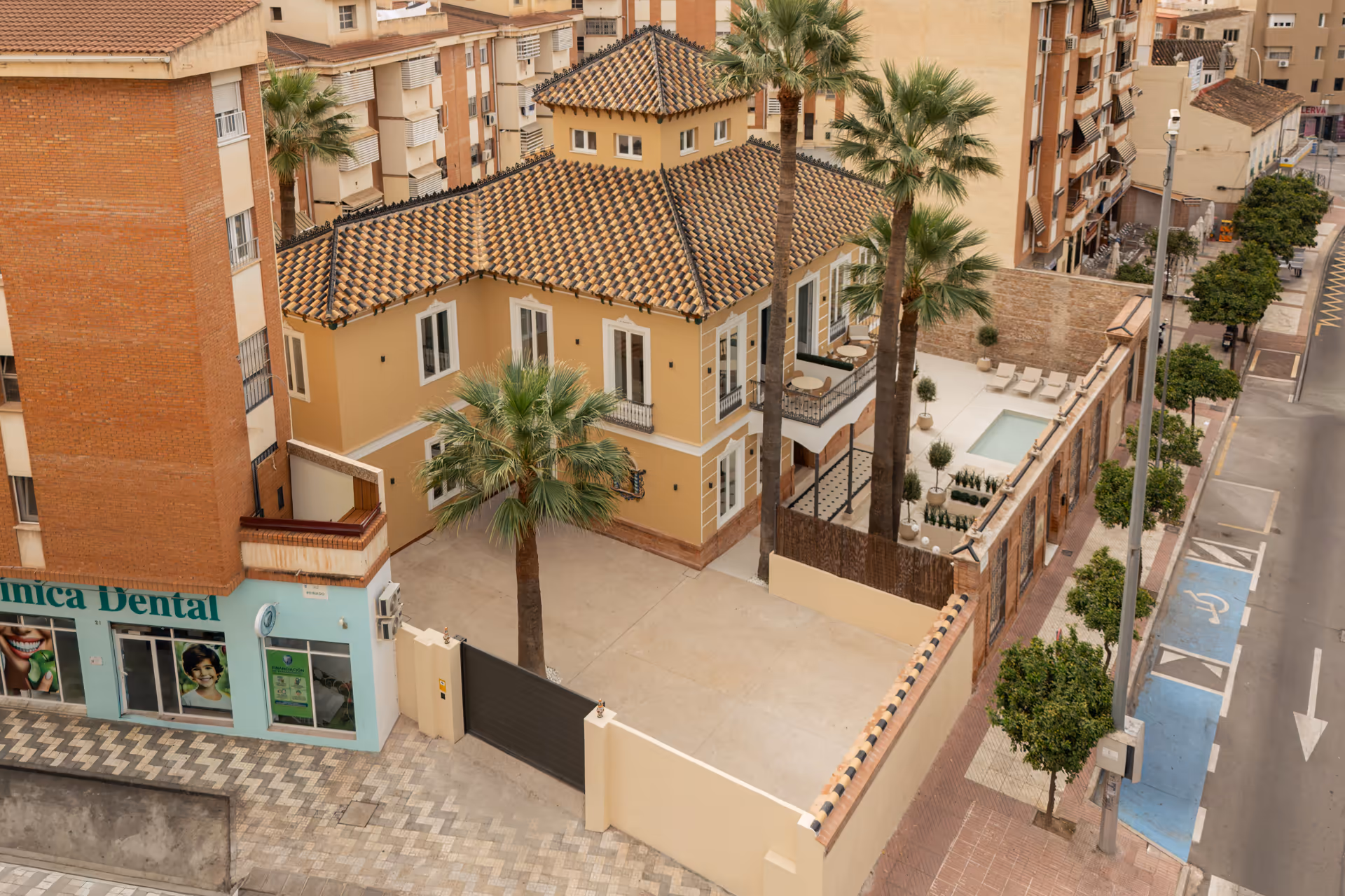 Aerial view of Palacete 10, a restored yellow villa with a tiled roof, its private courtyard and the courtyard pond