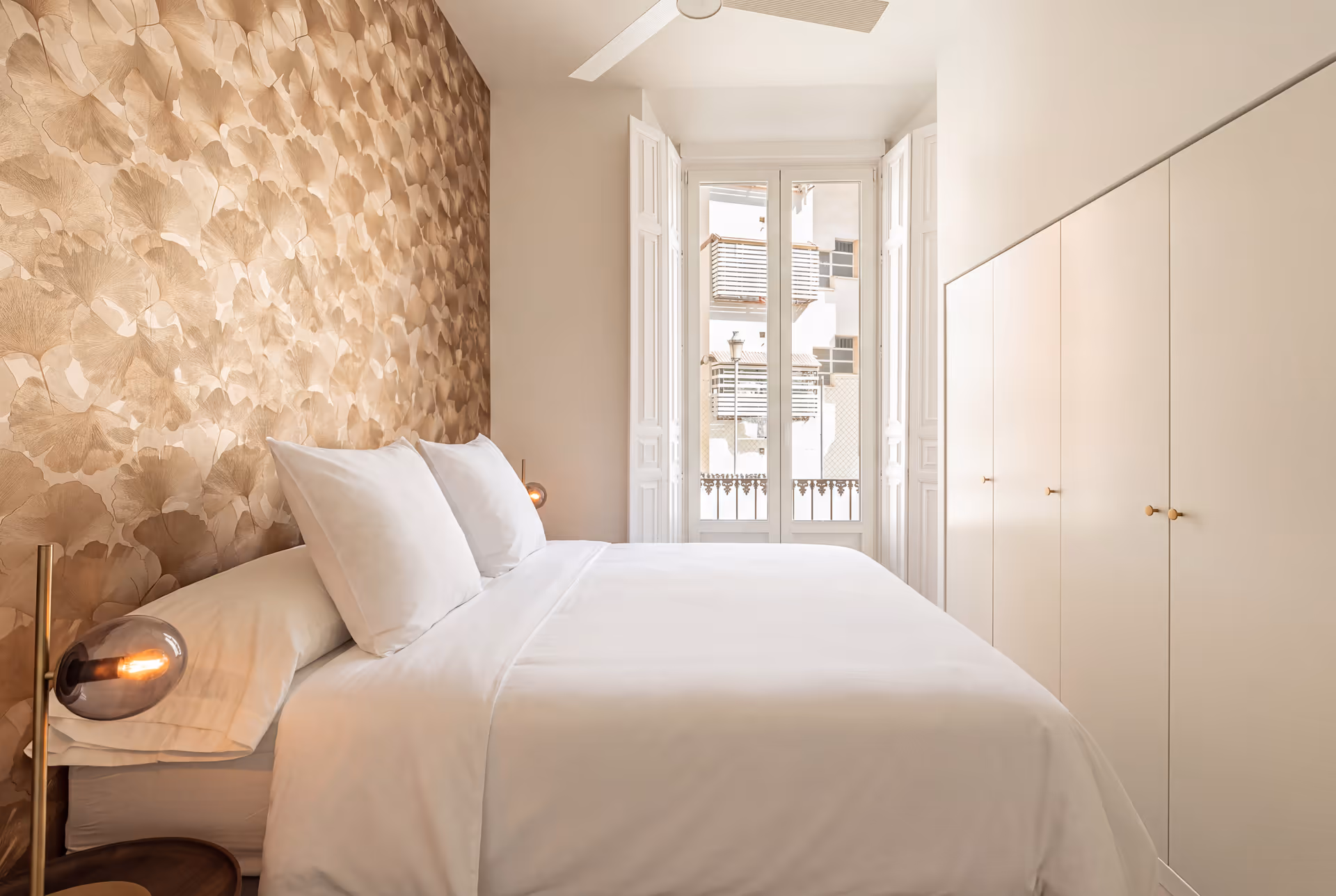 The Aurum residence bedroom, with a ginkgo leaf feature wall behind the bed and open French doors leading to a balcony