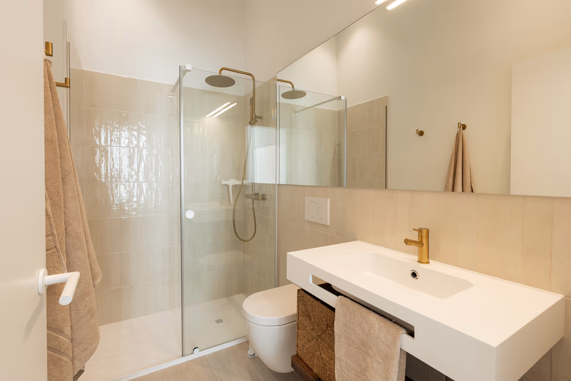 The bathroom in the Aurum residence, with a walk-in shower, white vanity unit, and brushed gold tapware and fittings