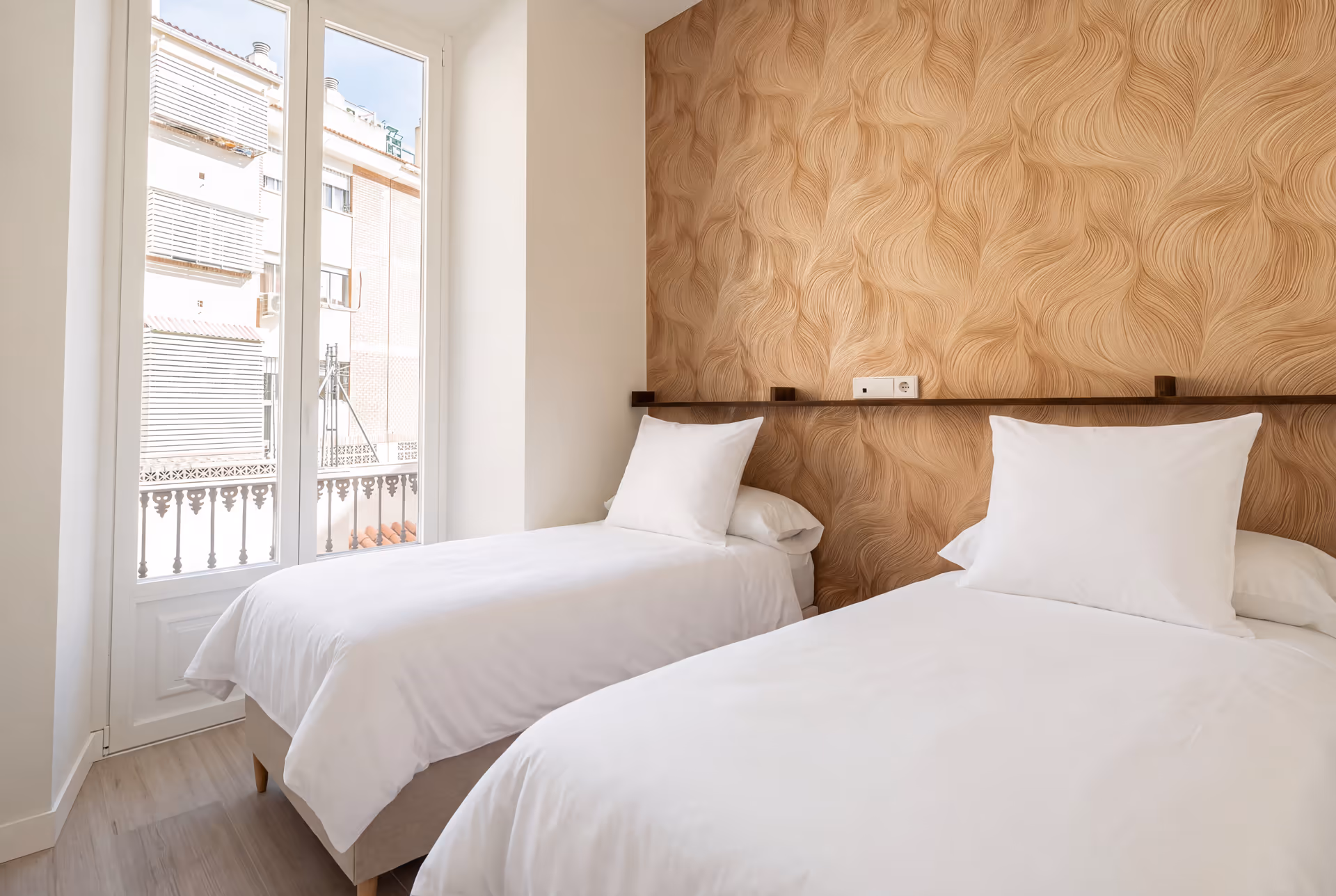 The twin bedroom in the Aurum residence, featuring textured gold wallpaper, two single beds, and a door to a balcony