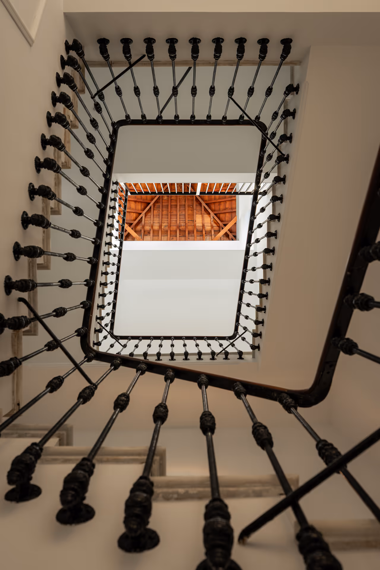 Looking up through the original 1908 staircase at Palacete 10, with its ornate iron balustrade and stone steps