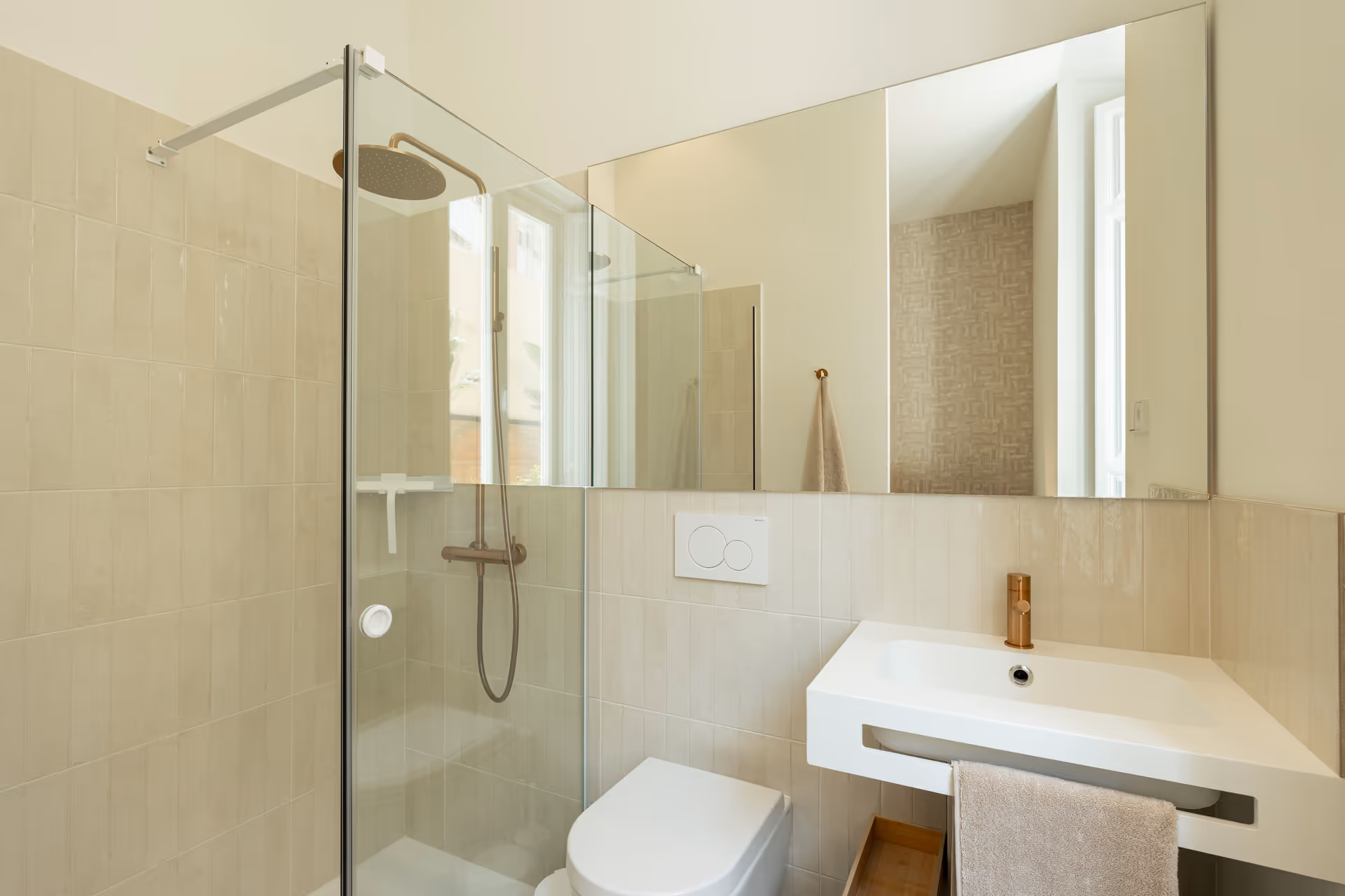 Bathroom in the Vino residence with a walk-in rain shower, wall-hung toilet, and a modern white sink with bronze tap