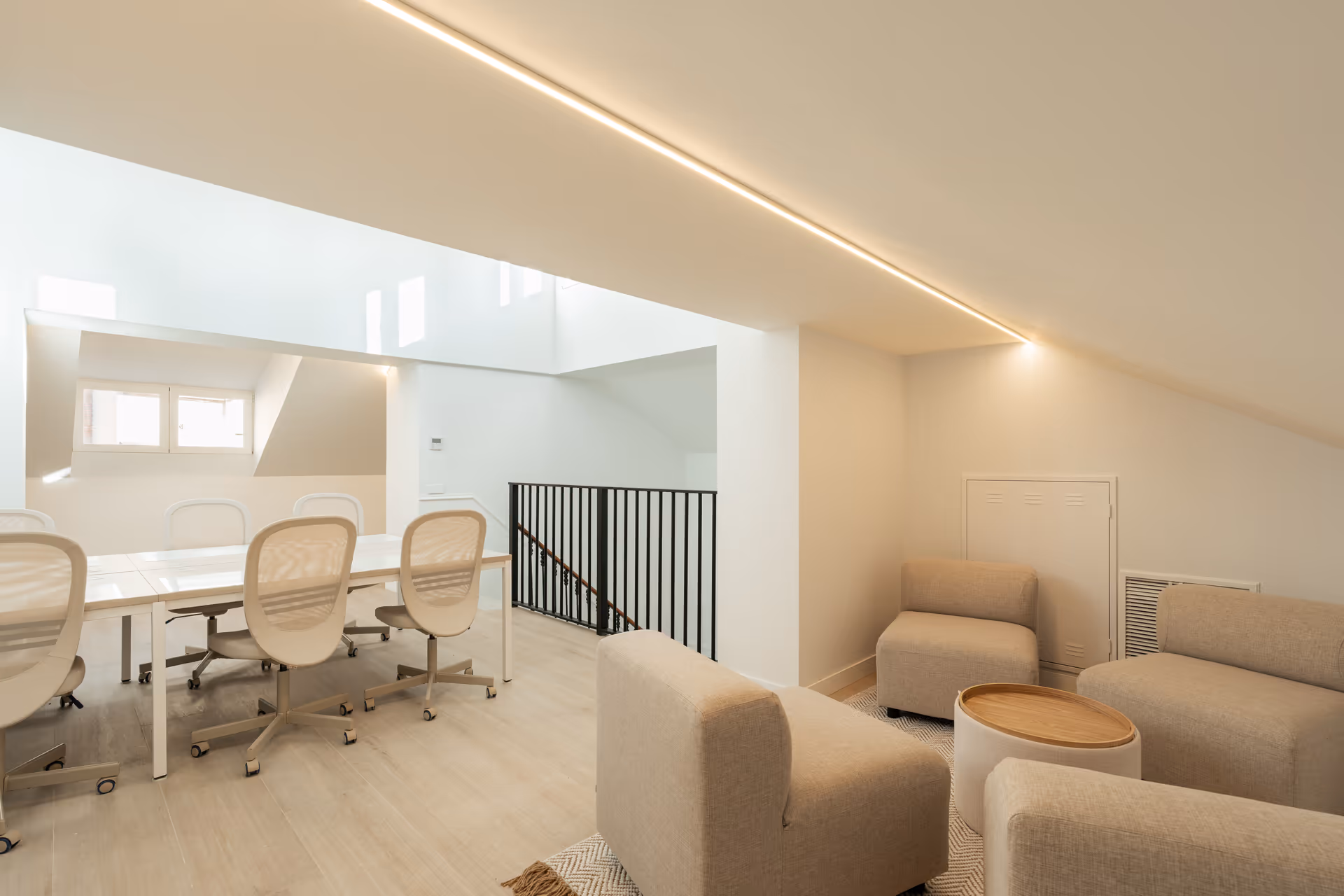 The bright attic work suite at Palacete 10, with a long shared table and a separate lounge area with armchairs