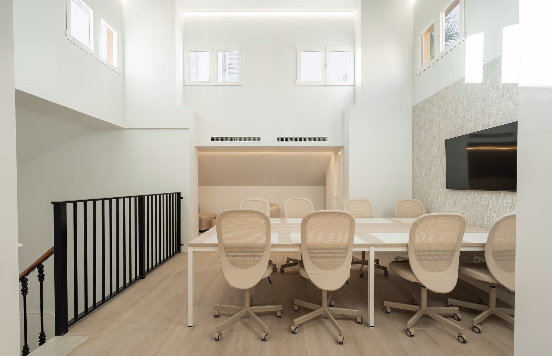 The bright, double-height work suite at Palacete 10, with a long shared table, mesh office chairs, and light wood floors