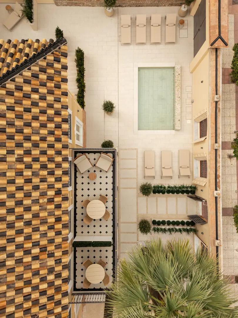 Aerial view of the Palacete 10 courtyard, with its central pond, sun loungers, and balconies with dining tables