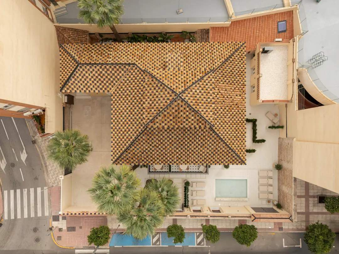 Aerial view of Palacete 10, showing the distinctive chequerboard tiled roof, courtyard with pond, and surrounding Málaga neighbourhood