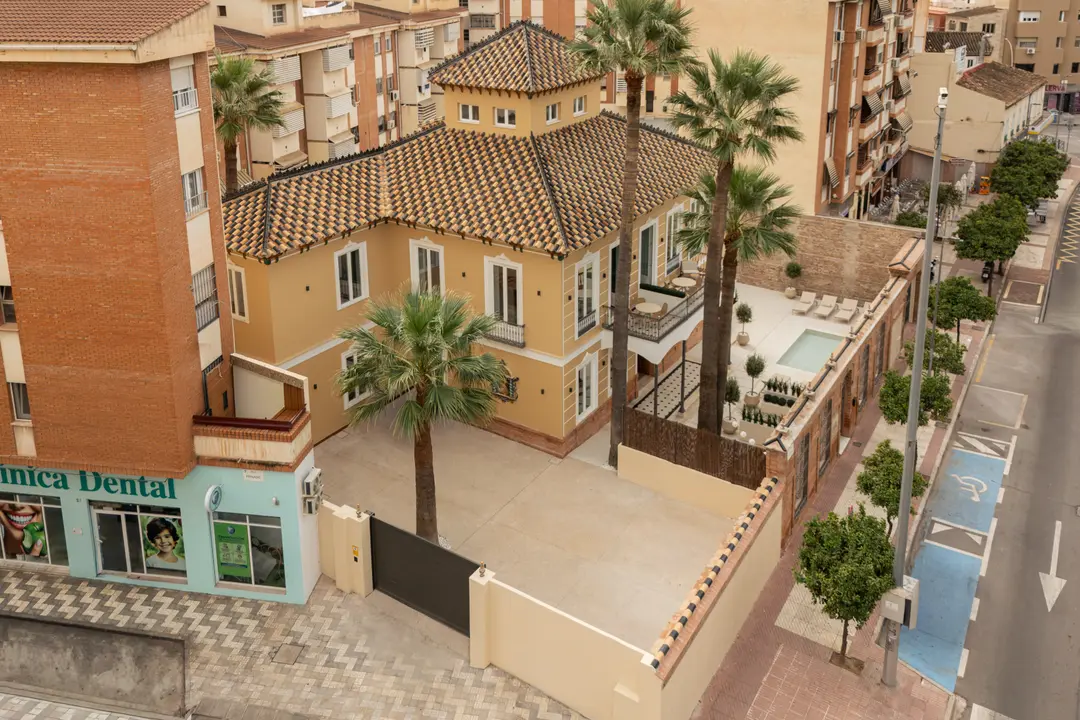 Aerial view of Palacete 10, a restored yellow villa with a tiled roof, its private courtyard and the courtyard pond