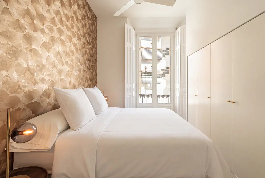 The Aurum residence bedroom, with a ginkgo leaf feature wall behind the bed and open French doors leading to a balcony