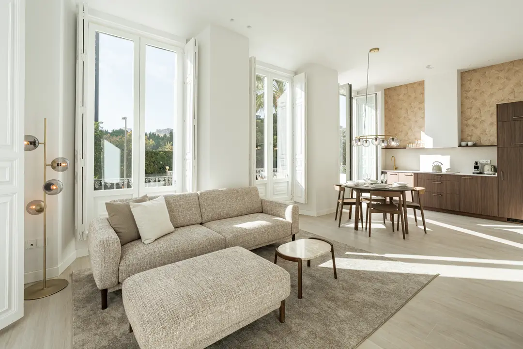 The bright, open-plan living area of the Aurum residence, with a textured sofa, wooden dining set, and modern kitchen