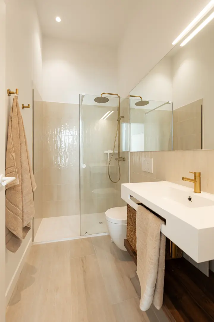 Aurum residence bathroom with a walk-in rain shower, high ceiling, and a white basin on a wood vanity unit