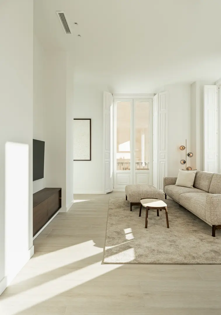 Sunlight streams into the living room of the Aurum residence, illuminating a beige sofa, light wood-effect flooring and a floating console