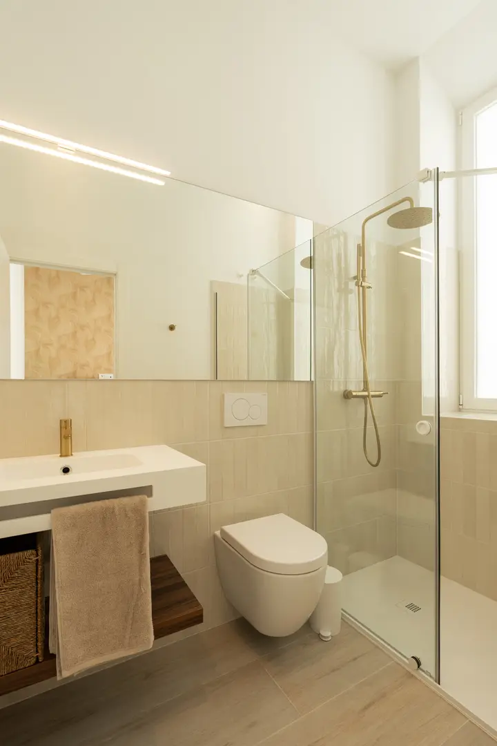 Aurum residence bathroom with a walk-in rain shower, wall-hung toilet, and a vanity with brushed gold tapware