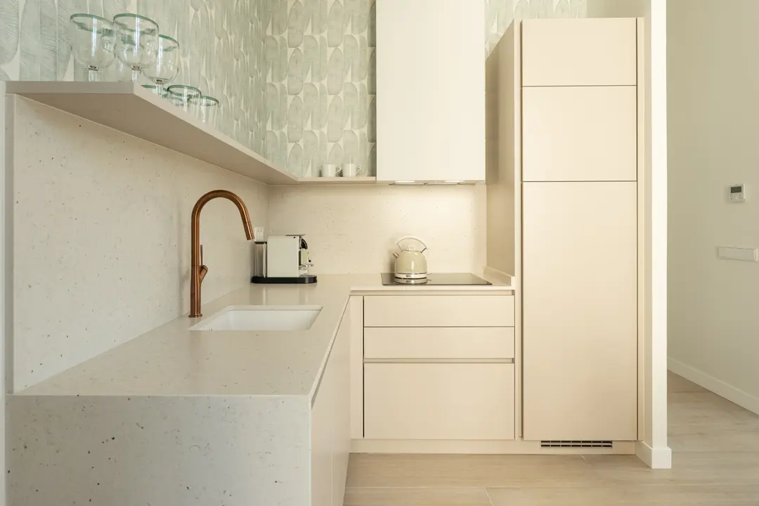 The kitchen in the Azuri residence, featuring cream cabinets, a terrazzo worktop, an integrated sink, and a copper tap