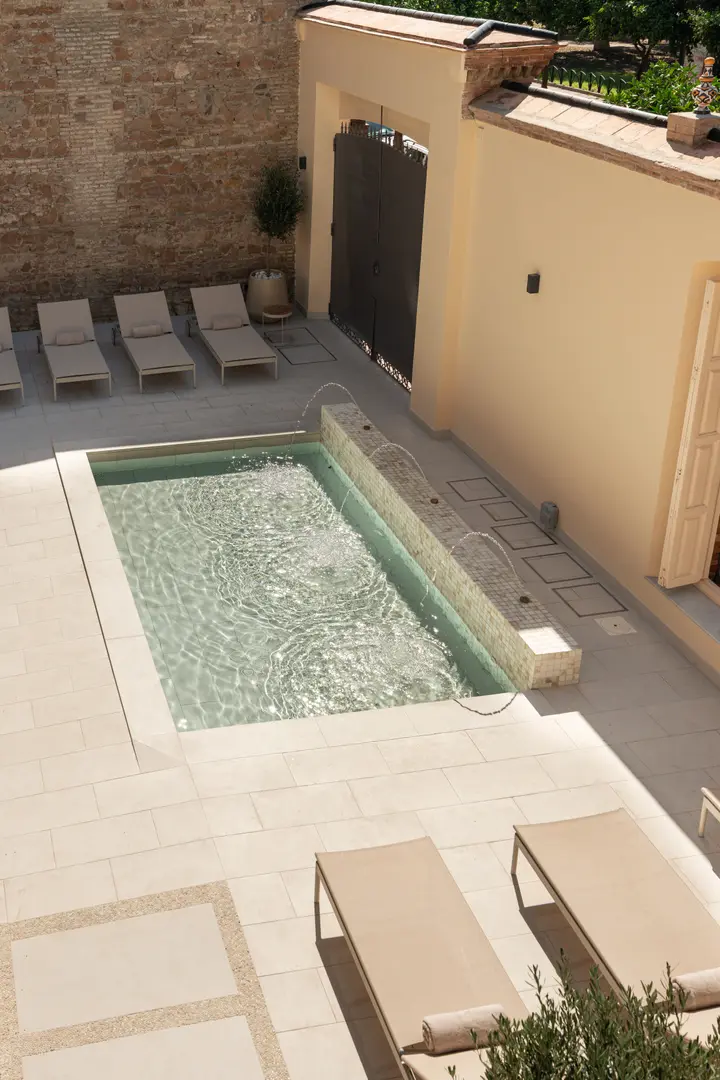 High-angle view from the Azuri residence of the shared courtyard, showing the pond with fountains and surrounding sun loungers