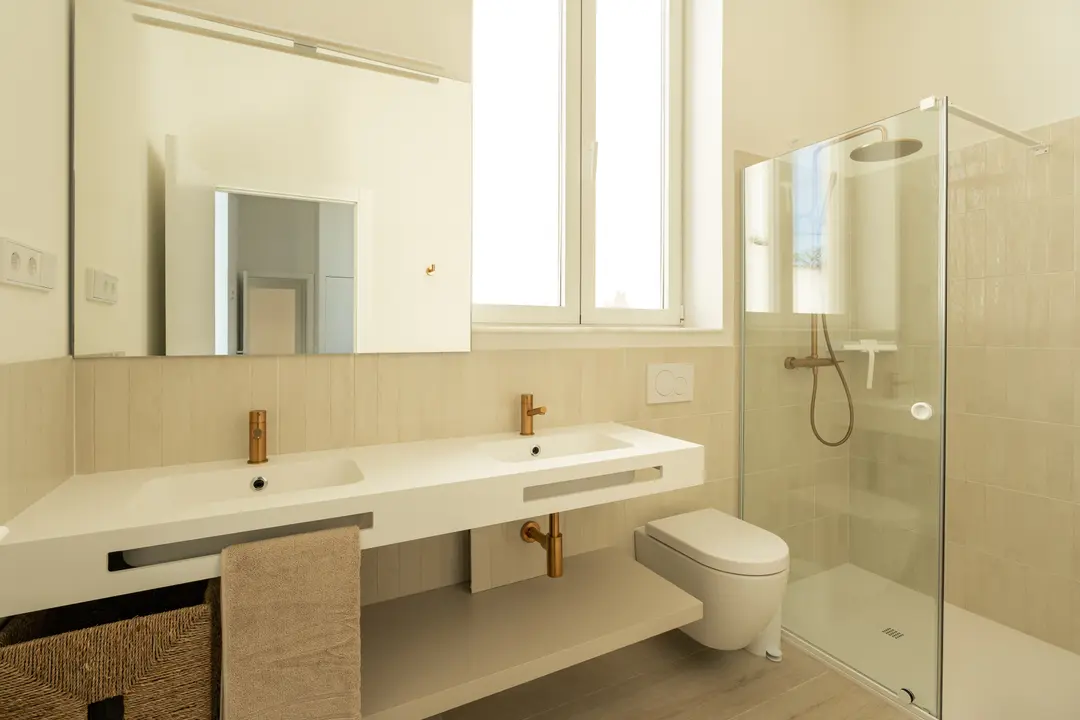The Azuri residence bathroom with a white double vanity, bronze taps, walk-in rain shower, and bright natural light