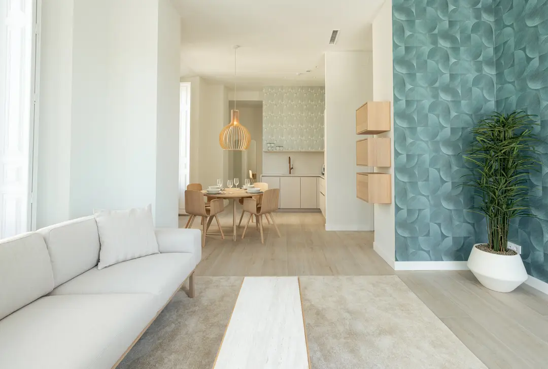 Bright living room in the Azuri residence with a white sofa, leading to the dining area and kitchen