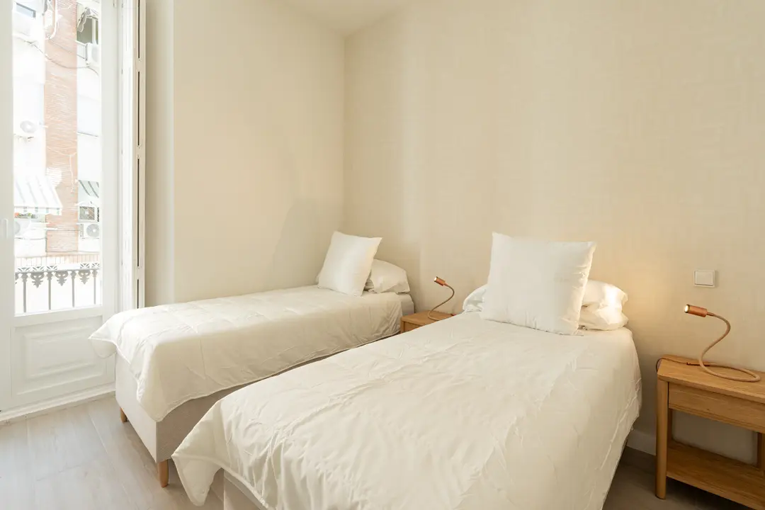Twin bedroom in the Azuri residence with two single beds, white bedding, and a glass door opening onto a balcony