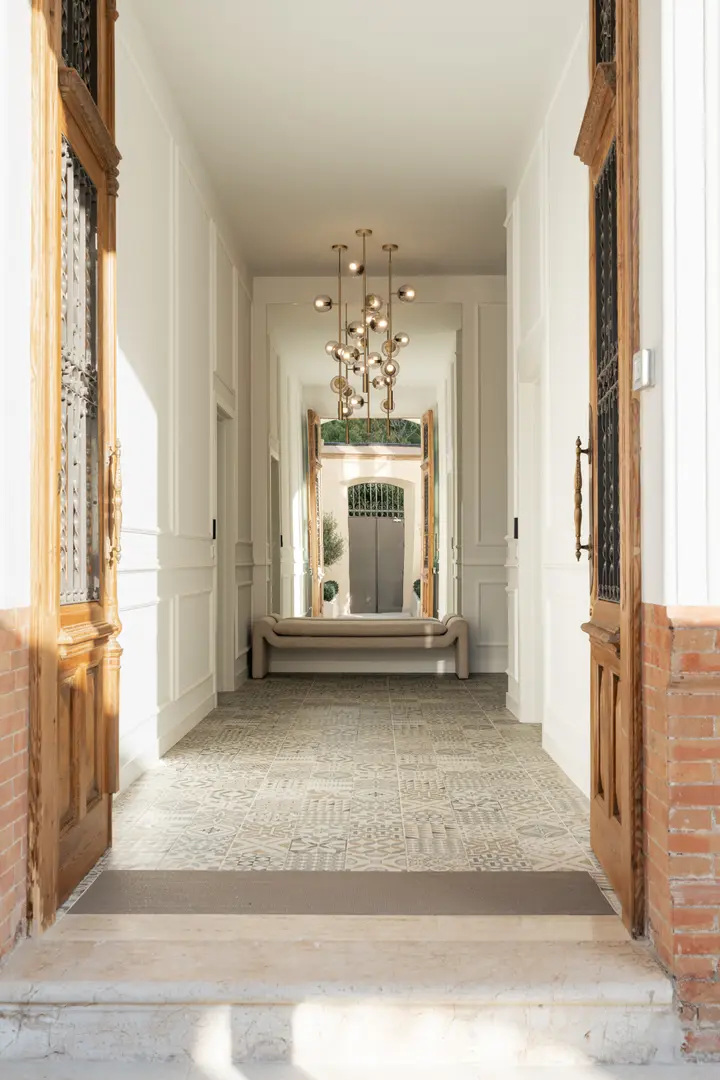 View from the front door down the long entrance hall of Palacete 10, with its patterned tiled floor and modern chandelier
