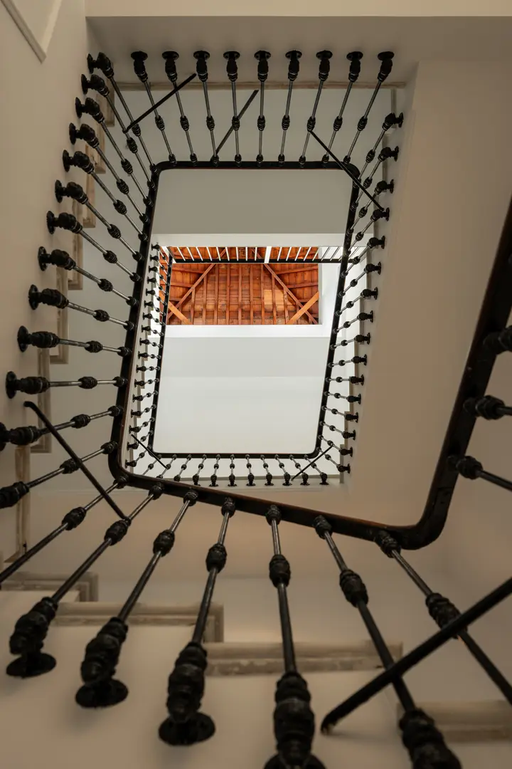 Looking up through the original 1908 staircase at Palacete 10, with its ornate iron balustrade and stone steps