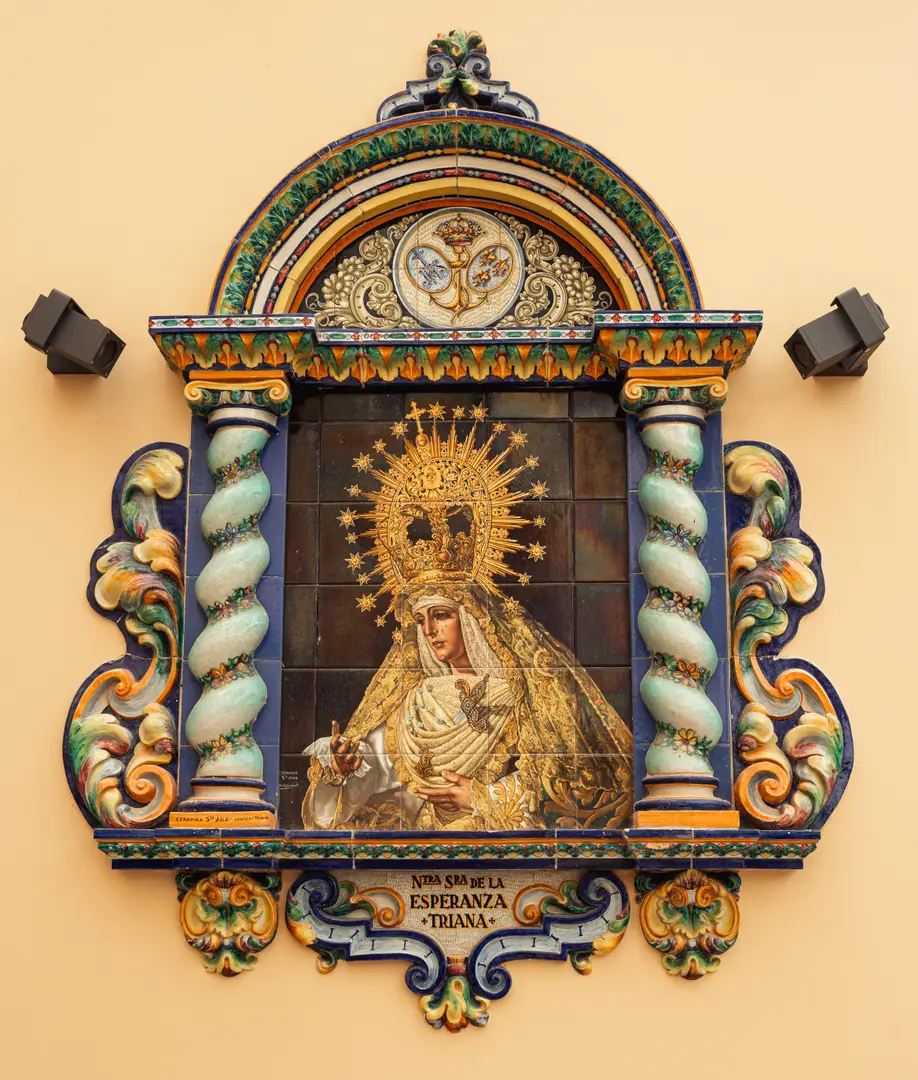 Ornate ceramic tile mural of the Virgin Mary on the yellow facade of Palacete 10, framed by columns and an arch