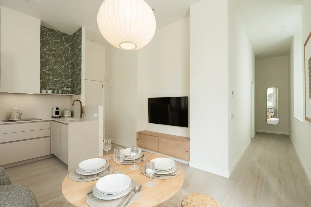 The open-plan living area in the Oliva residence, with a round dining table under a spherical lantern and a compact kitchen