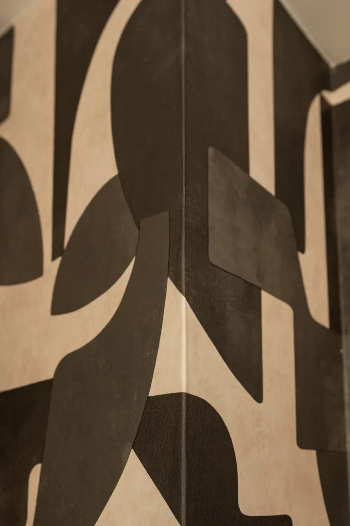 Close-up of the textured wallpaper in the Toro residence, showing its bold, abstract pattern in black and beige tones