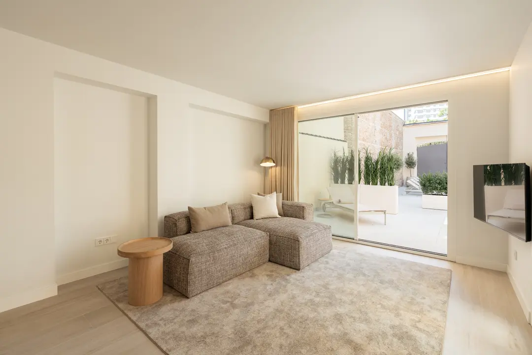 Living room in the Toro residence with a large chaise sofa, wooden side table, and sliding doors to a private terrace