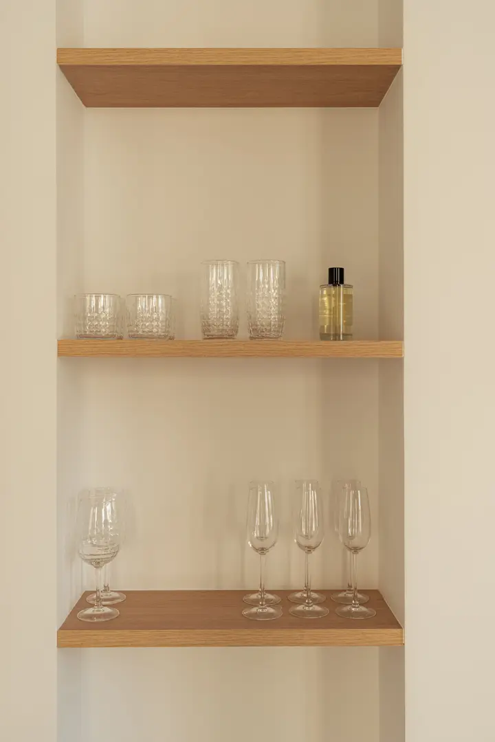 A detail of built-in oak shelves in the Toro residence, neatly arranged with cut-glass tumblers, flutes and wine glasses