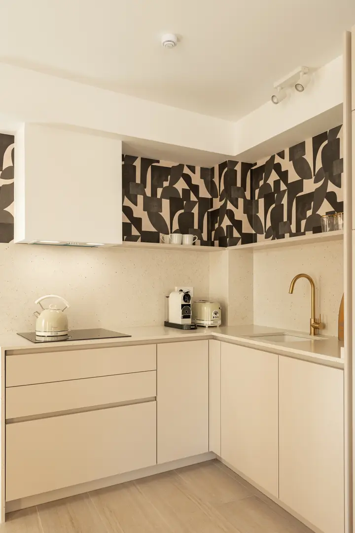 The kitchen in the Toro residence, with cream cabinets, a brass tap, and a bold black and cream patterned wall