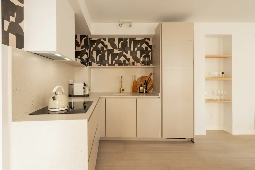 The kitchen in the Toro residence has cream cabinets, a stone worktop, and a bold black and cream patterned backsplash
