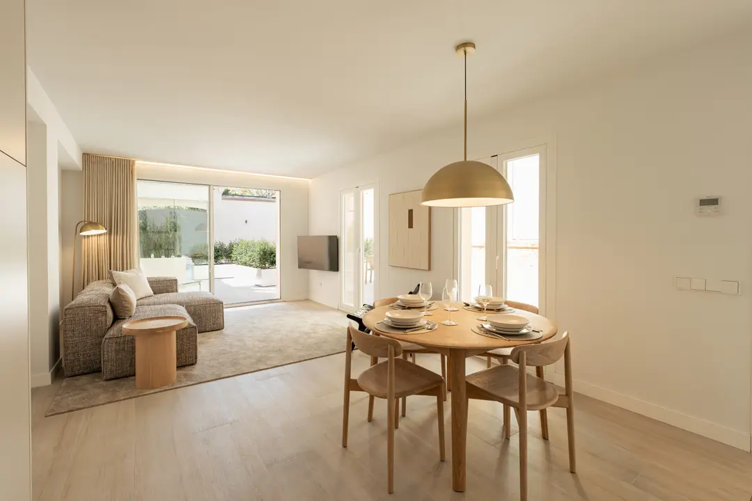 The open-plan living and dining room of the Toro residence, with a wooden dining table and a textured sofa
