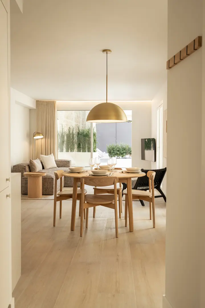 The open-plan living and dining area in the Toro residence, with a round wooden table under a brass pendant light