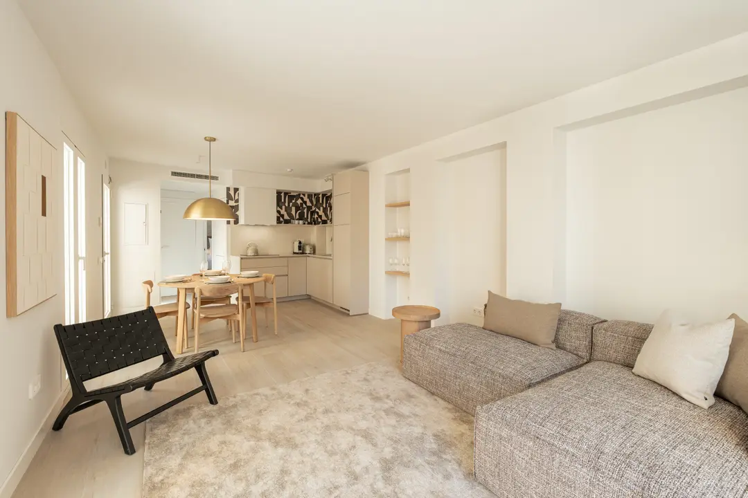 The bright, open-plan living space in the Toro residence, with a textured sofa, light wood floors, and dining area and kitchen beyond
