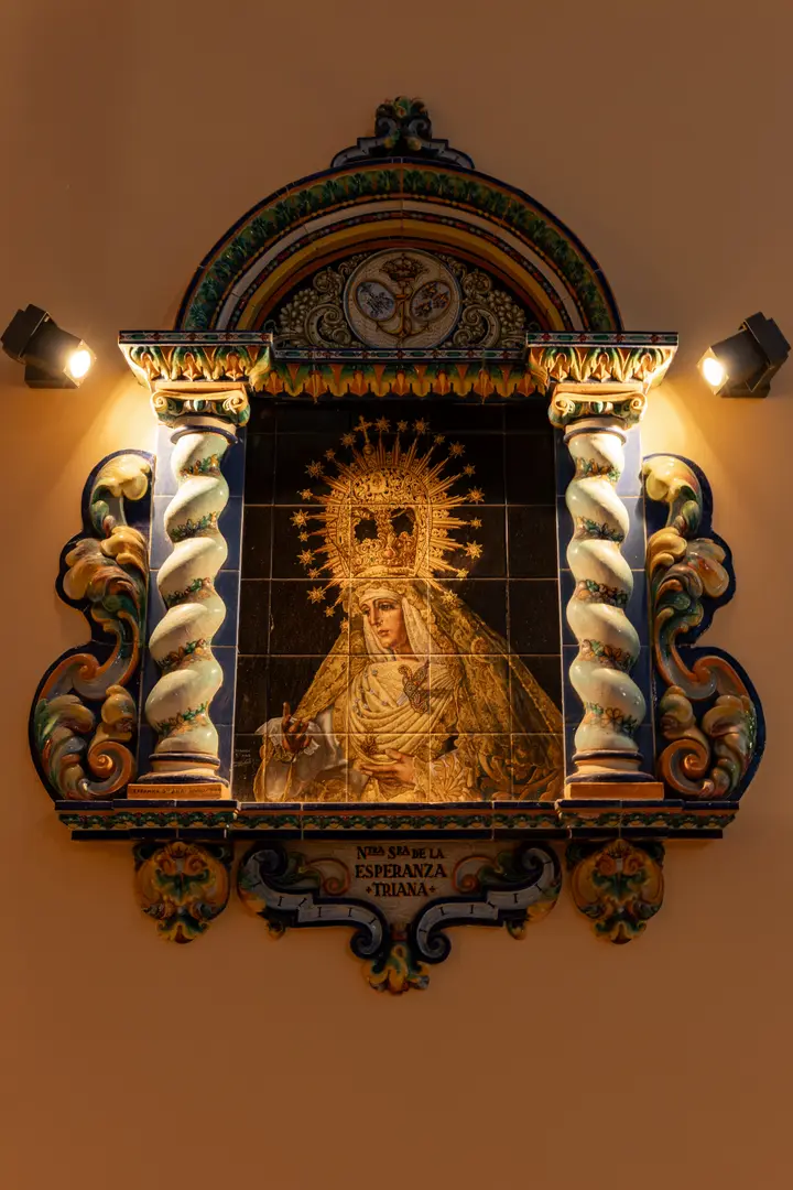 Close-up of a traditional ceramic shrine of the Virgin Mary, illuminated by warm spotlights on a courtyard wall at Palacete 10