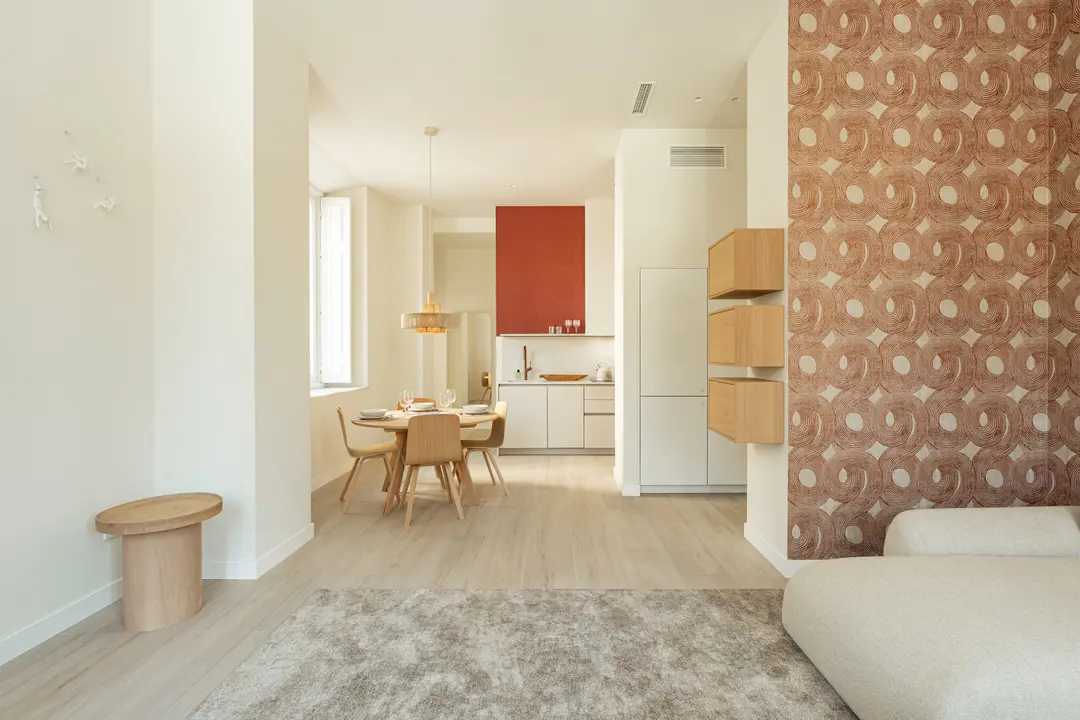 View from the living room of the Vino residence across the dining area to the open-plan kitchen with a red accent wall