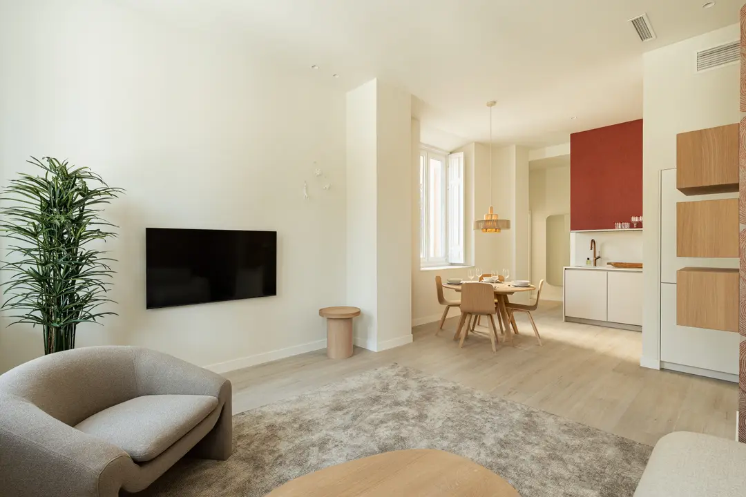 Open-plan living and dining area in the Vino residence, with light wood floors and a grey armchair and rug