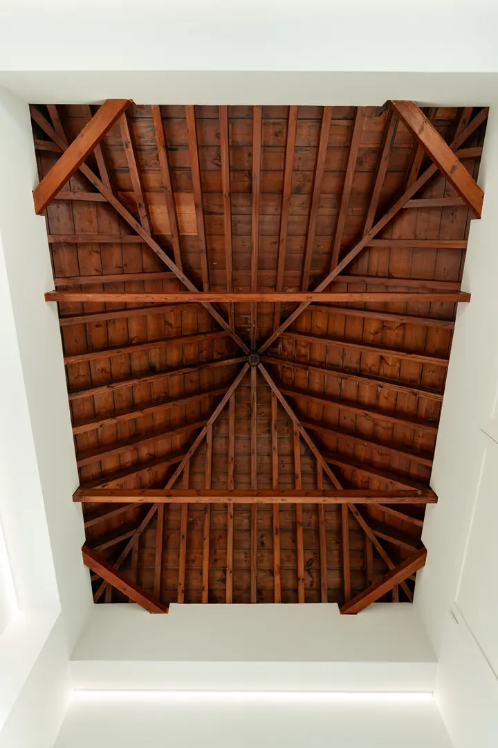 Looking up at the restored dark wood beams and rafters of the ceiling in the attic work suite