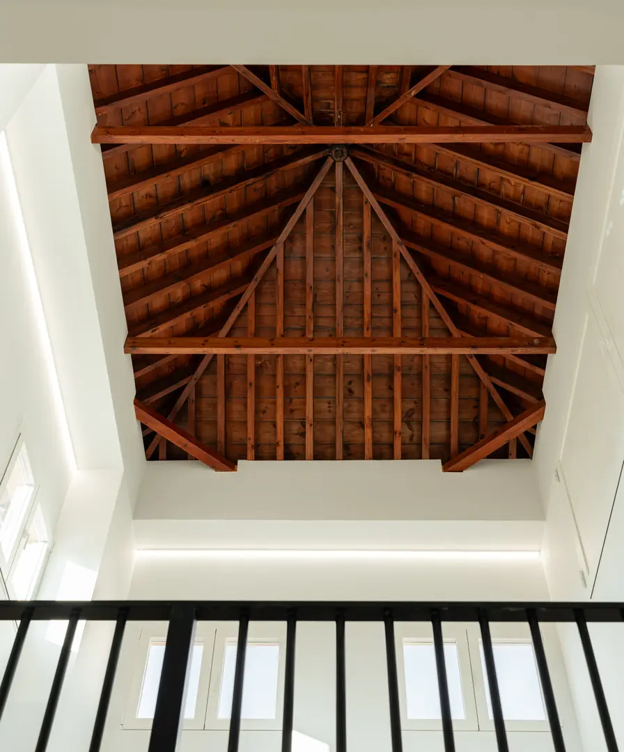 Looking up at the restored pitched wooden ceiling with exposed beams in the attic work suite at Palacete 10